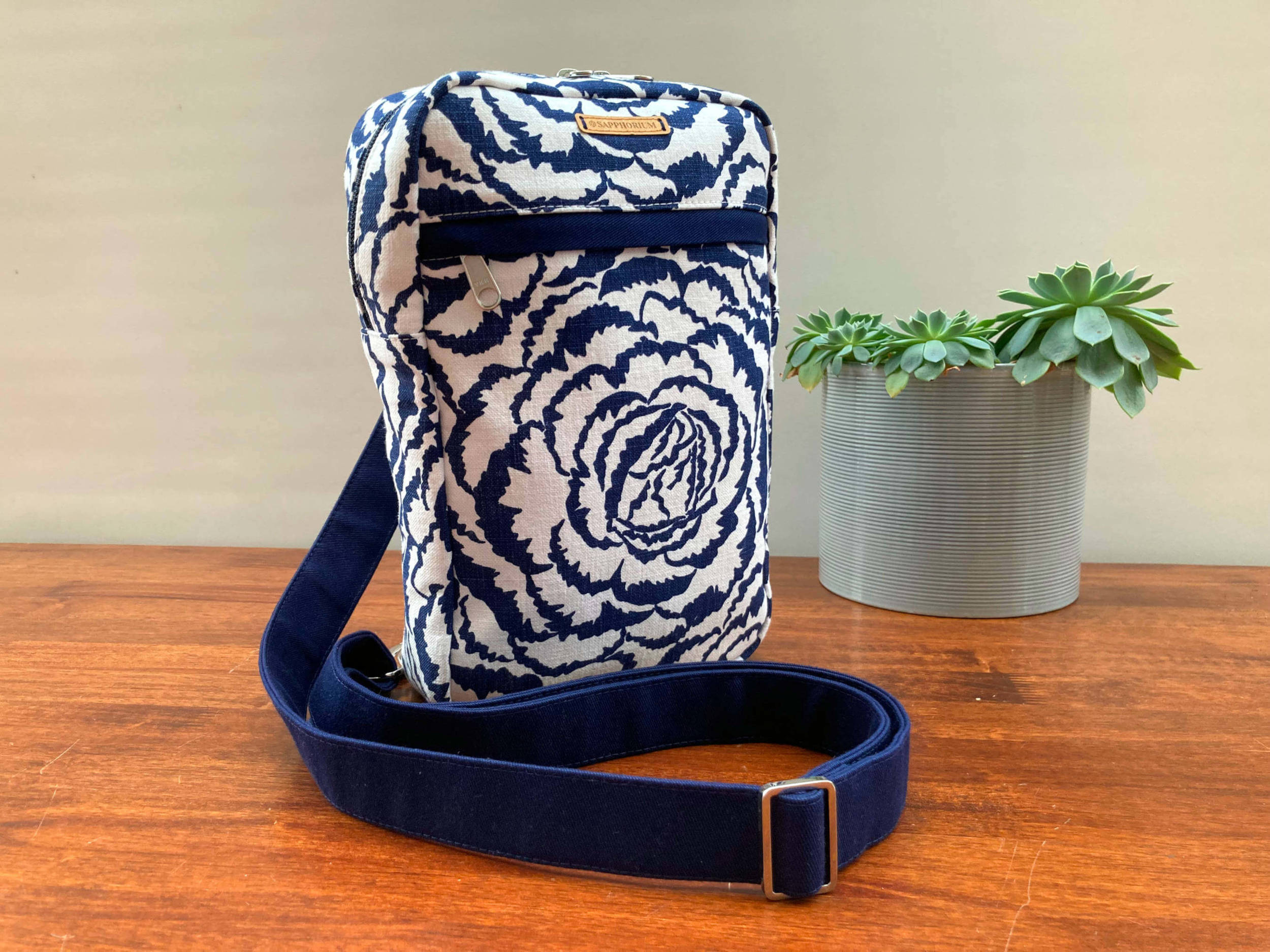 Blue and White Roses Sling on wooden table with a pot plant to the side. Handmade by Sapphorium.