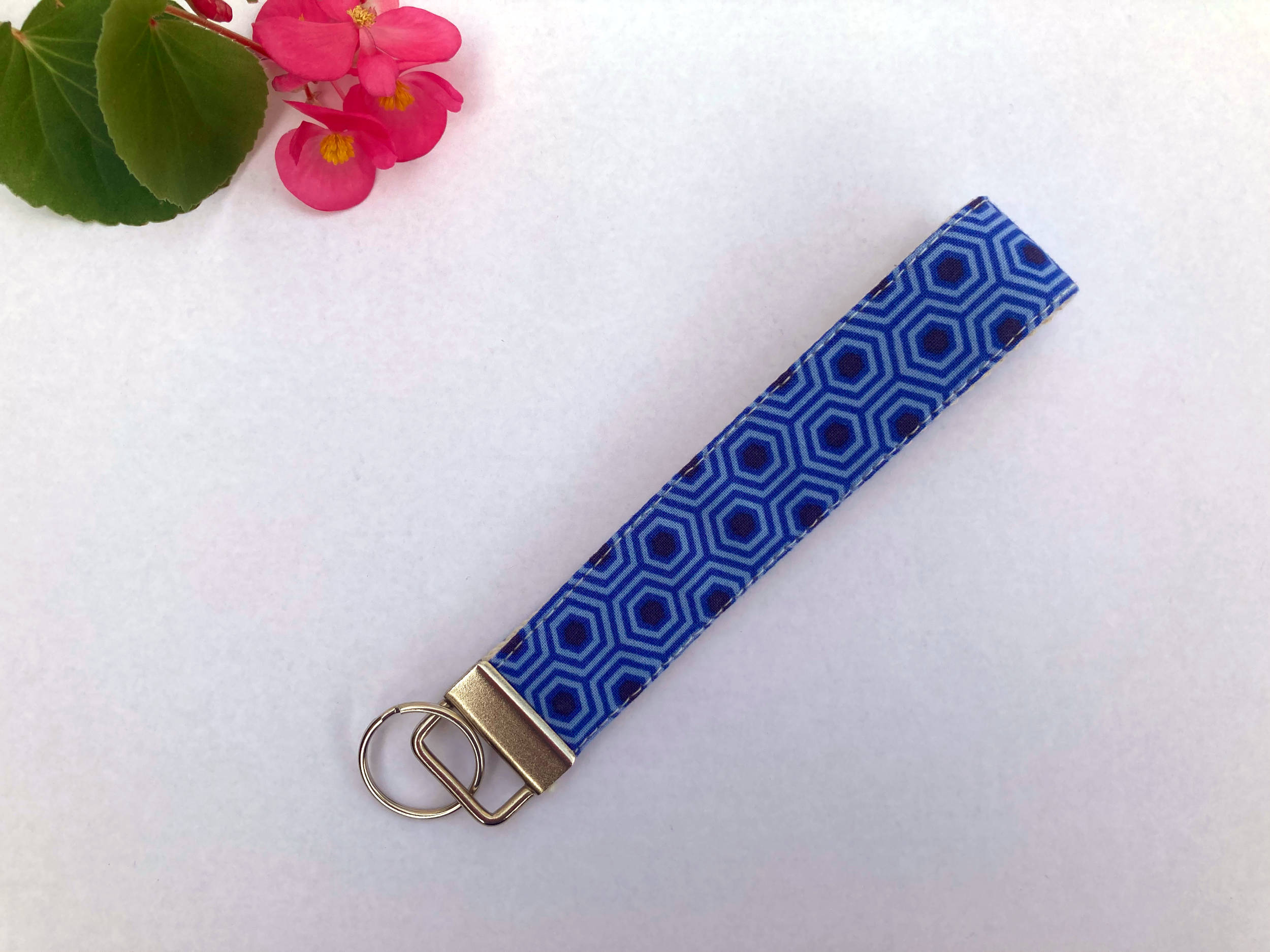 Key fob with a blue hexagon print on a table next to a pink flower