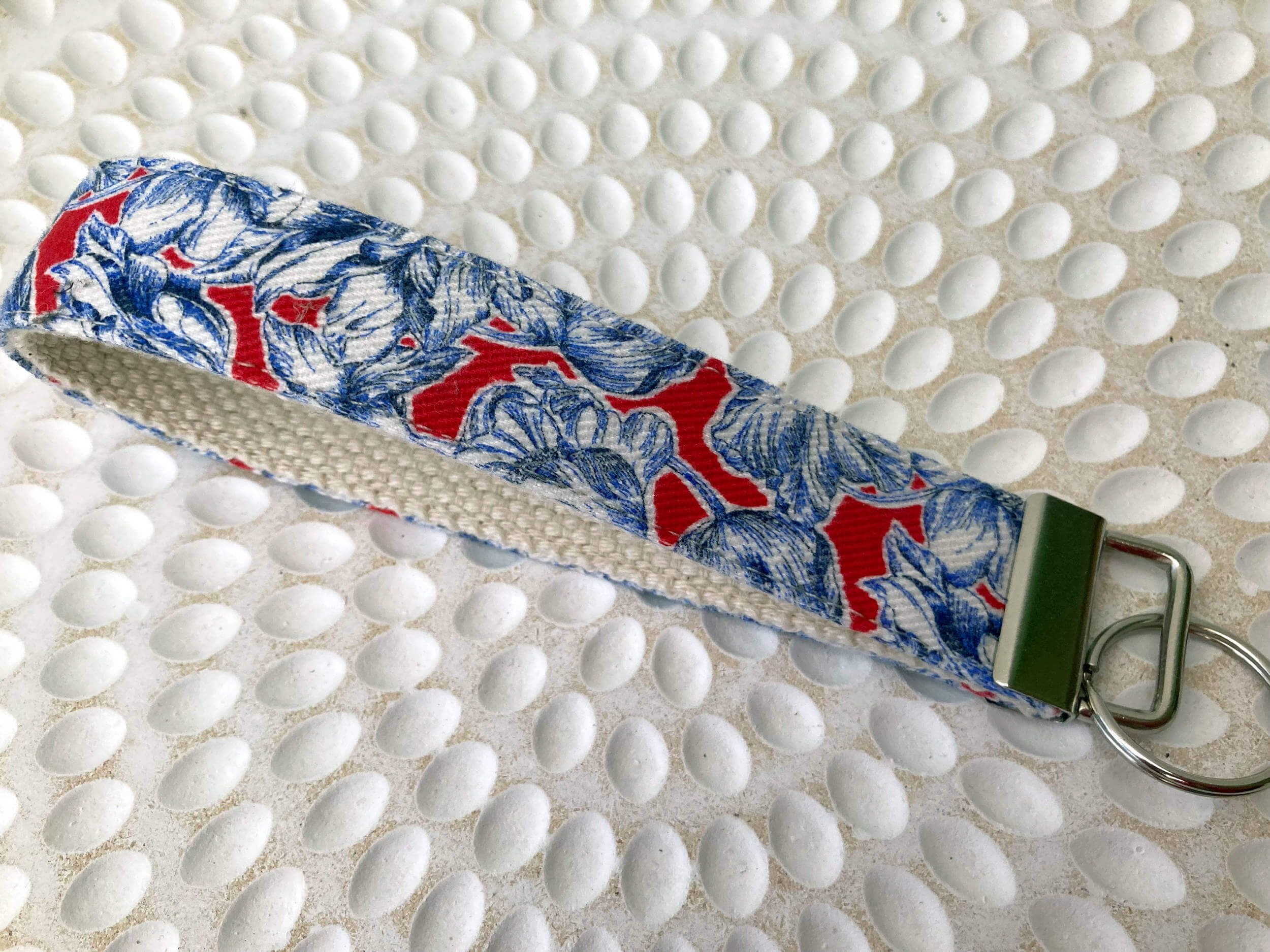 Textured plate with key fob on it that is blue and white floral with red. Key fob has a few keys on it.