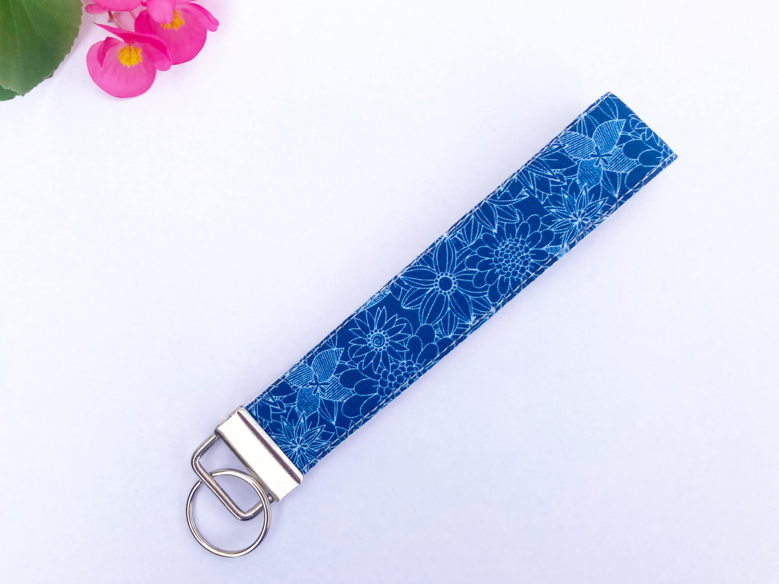 Fabric Key fob in a navy floral print on a white background with pink flowers in the corner.