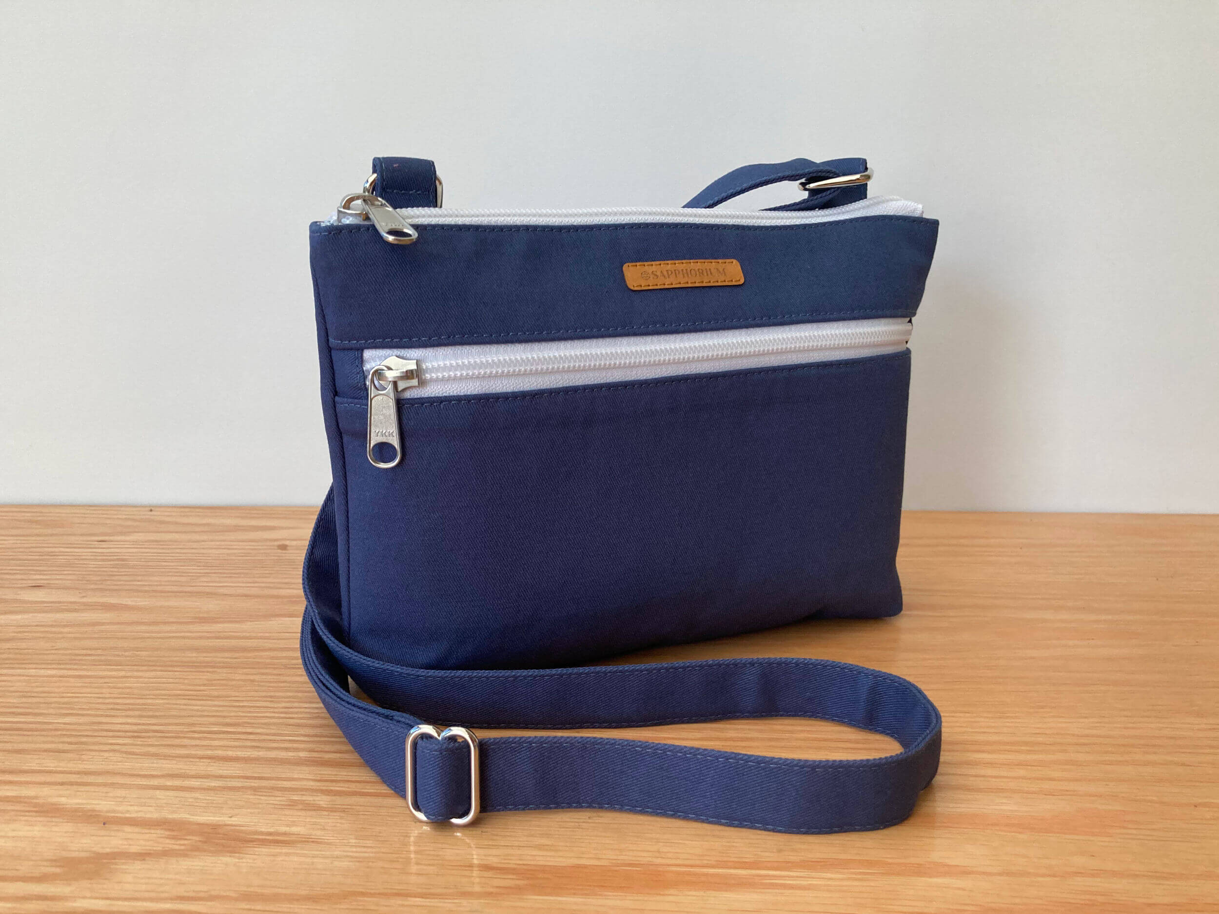 Marine Blue Crossbody Bag on a wooden table and white background.